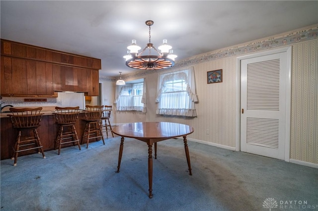 dining area featuring wallpapered walls, an inviting chandelier, light carpet, and baseboards