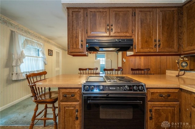 kitchen with wallpapered walls, light countertops, under cabinet range hood, and black range with electric stovetop