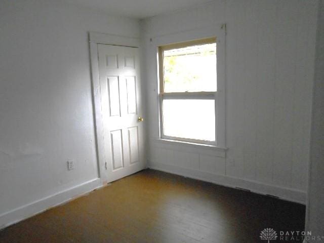 spare room with baseboards and wood finished floors