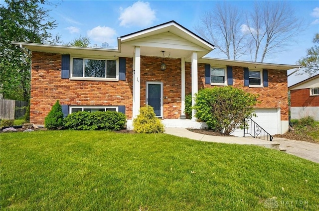 split foyer home with fence, brick siding, a garage, a front yard, and concrete driveway