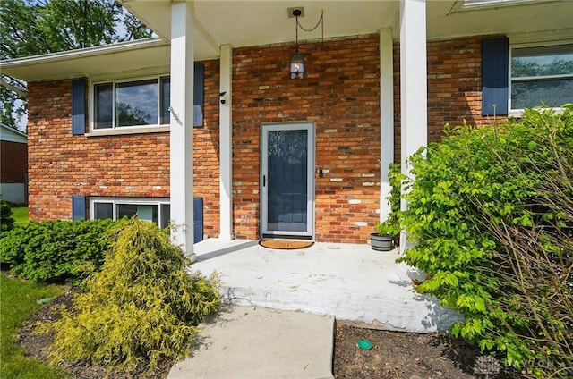 property entrance featuring covered porch and brick siding