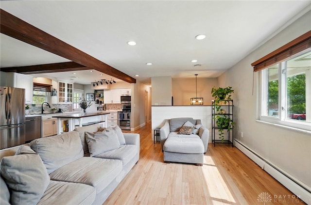 living area with beam ceiling, baseboards, light wood-style floors, baseboard heating, and recessed lighting