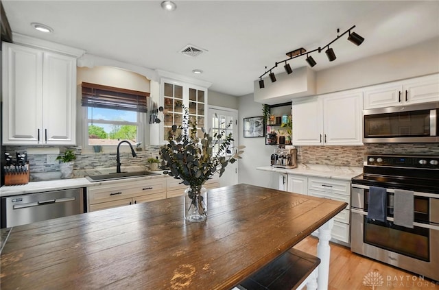 kitchen with white cabinets, a sink, stainless steel appliances, decorative backsplash, and visible vents