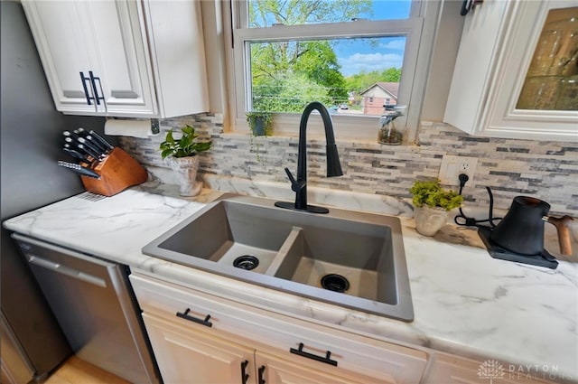 room details with a sink, tasteful backsplash, light stone countertops, and dishwasher