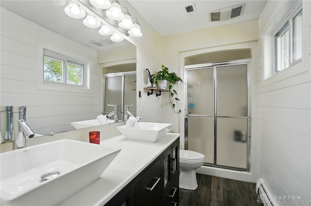 full bath featuring visible vents, a sink, wood finished floors, and a shower stall