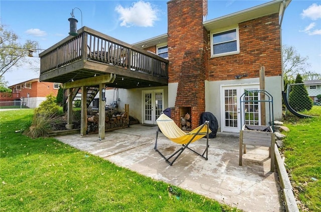 back of house featuring french doors, a lawn, a wooden deck, a patio, and stucco siding