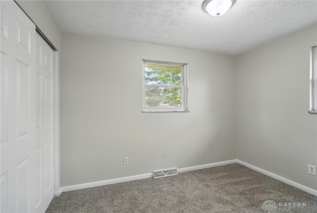 59 Janet Ave, Carlisle, OH 45005 - unfurnished bedroom featuring visible vents, a closet, baseboards, a textured ceiling, and carpet flooring