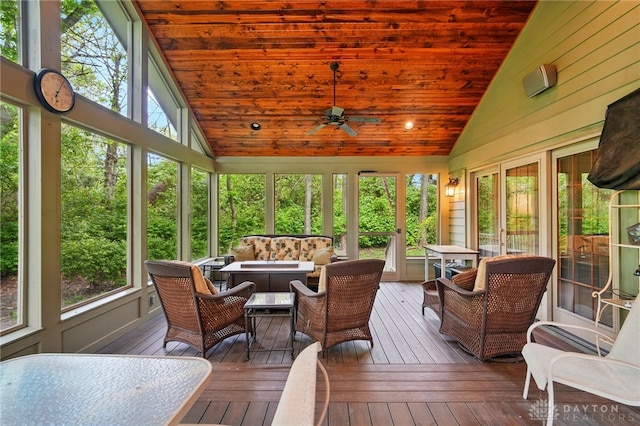 sunroom with plenty of natural light, an outdoor living space with a fire pit, and a ceiling fan