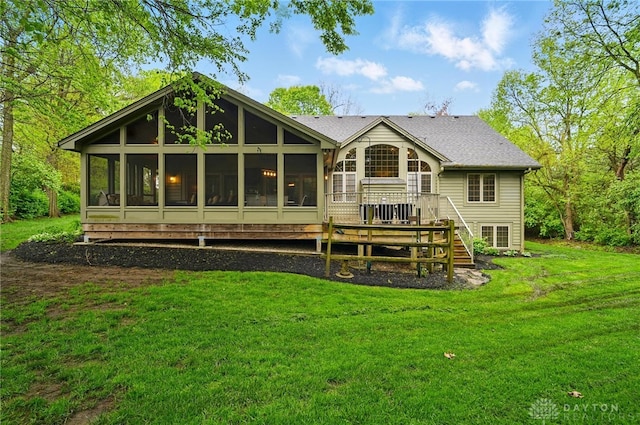 back of property featuring a yard, a shingled roof, a sunroom, and a deck