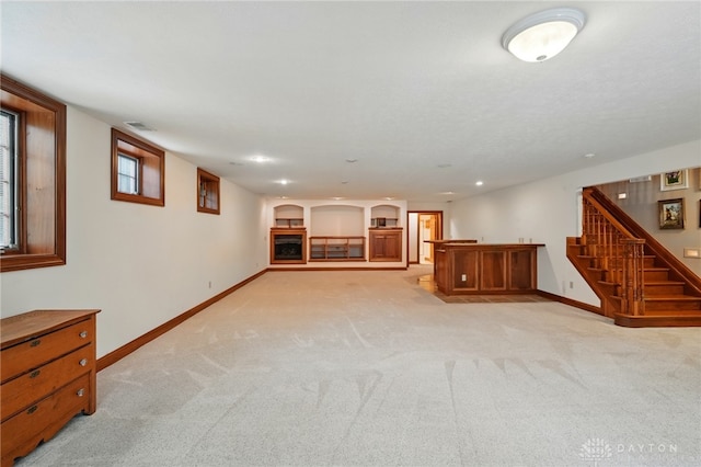finished basement with visible vents, stairs, light carpet, baseboards, and recessed lighting