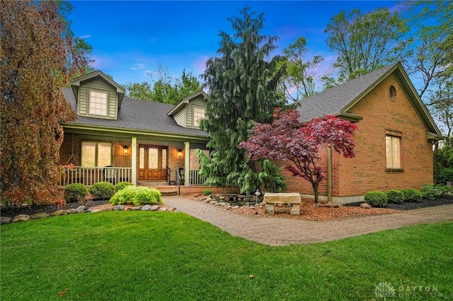 view of front of property featuring a yard, brick siding, and a porch