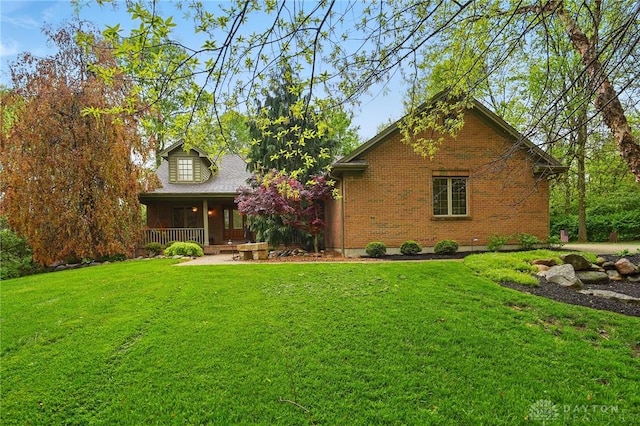 view of front of home with a porch, brick siding, and a front yard