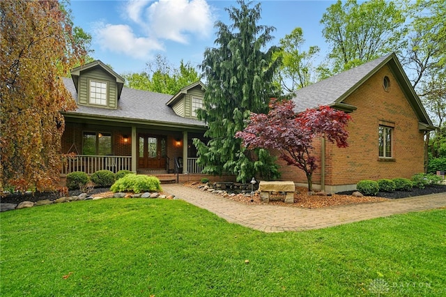 view of front of property featuring roof with shingles, a porch, a front lawn, and brick siding