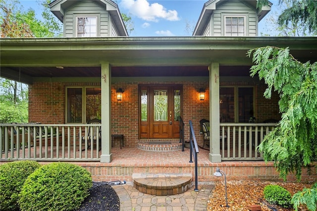 property entrance featuring covered porch and brick siding