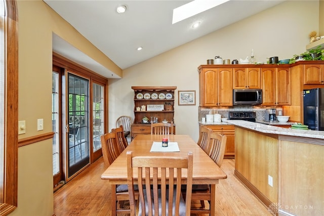 dining area featuring recessed lighting, light wood-style flooring, high vaulted ceiling, and a skylight