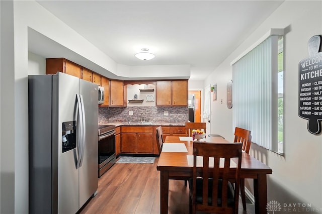 317 Ironwood Dr, West Carrollton, OH 45449 - kitchen with stainless steel appliances, brown cabinets, light wood finished floors, backsplash, and a sink