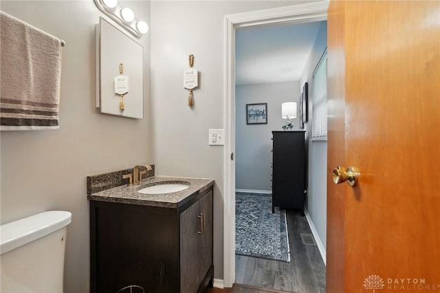 317 Ironwood Dr, West Carrollton, OH 45449 - half bathroom featuring vanity, wood finished floors, toilet, and baseboards