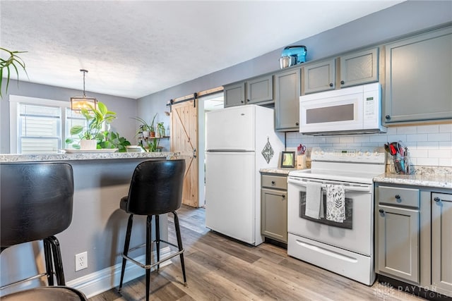 19 Klee Ave, Dayton, OH 45403 - kitchen with white appliances, gray cabinetry, a barn door, decorative backsplash, and light wood-type flooring
