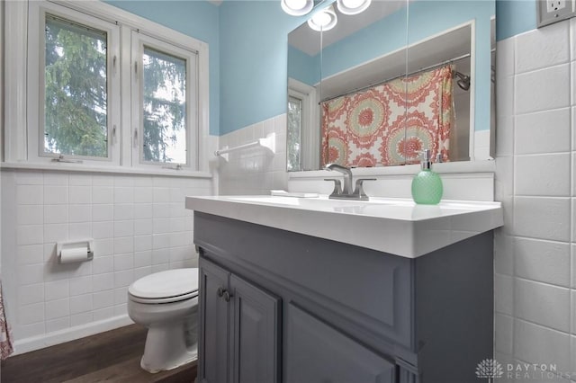 full bath with vanity, wainscoting, wood finished floors, toilet, and tile walls