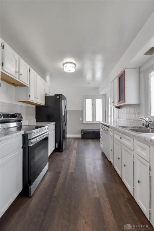 kitchen with plenty of natural light, a sink, white cabinetry, and stainless steel electric range oven