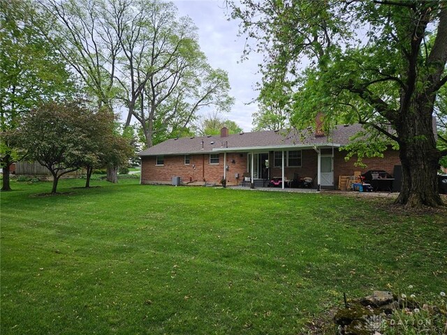 403 W Rahn Rd, Dayton, OH 45429 - rear view of property with brick siding, a yard, a chimney, and a patio