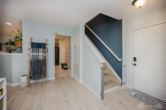 foyer entrance with baseboards, visible vents, stairway, and light wood-style floors