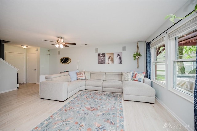 living room with light wood-style floors, a ceiling fan, and baseboards