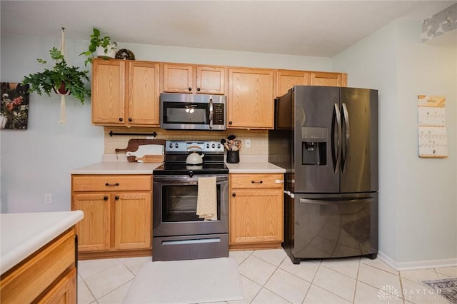 kitchen with light countertops, stainless steel appliances, light tile patterned flooring, and tasteful backsplash