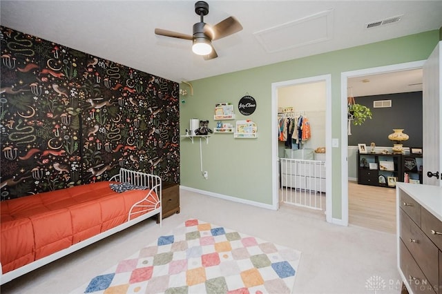 carpeted bedroom with baseboards, a ceiling fan, attic access, and visible vents