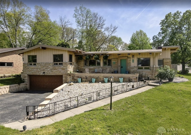 exterior space featuring board and batten siding, driveway, a garage, fence, and stone siding