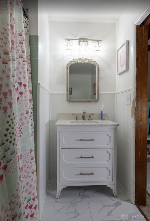 full bathroom with a wainscoted wall, a shower with shower curtain, vanity, and marble finish floor