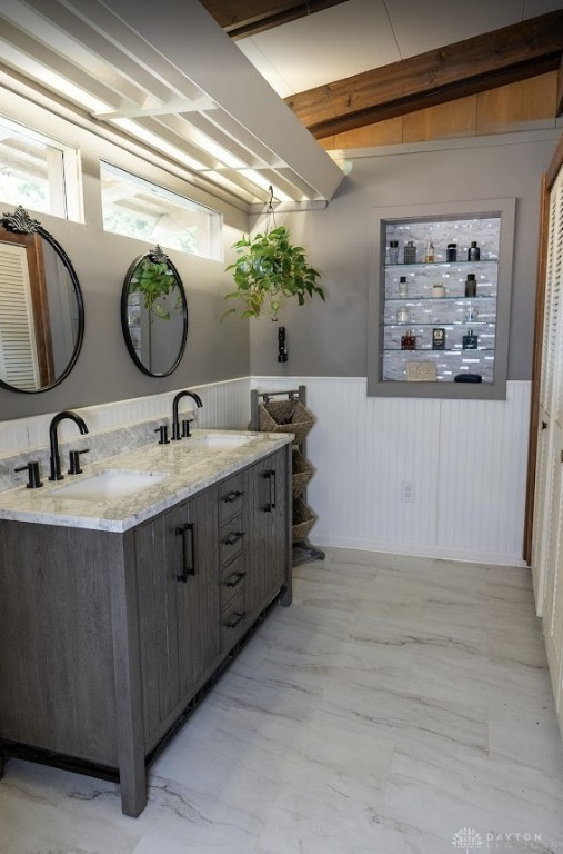 bathroom featuring a sink, wainscoting, double vanity, and marble finish floor