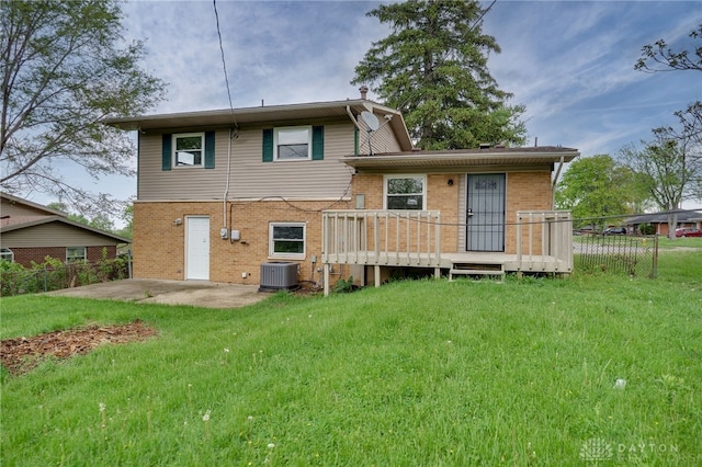 back of house featuring brick siding, central AC unit, a lawn, and fence