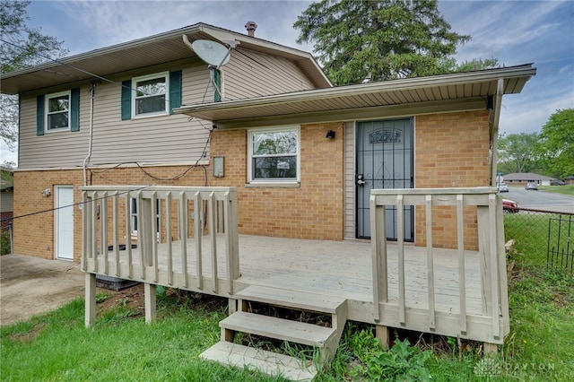 back of house featuring brick siding, fence, and a wooden deck