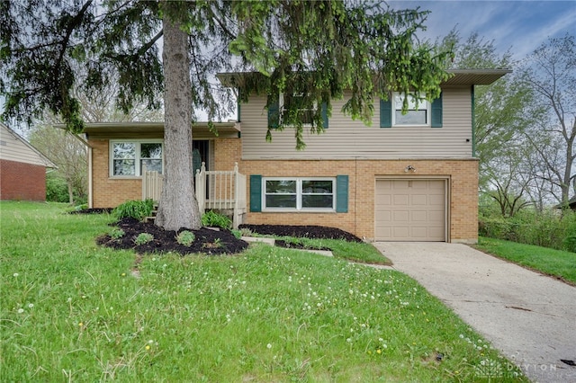 split level home featuring brick siding, an attached garage, driveway, and a front yard