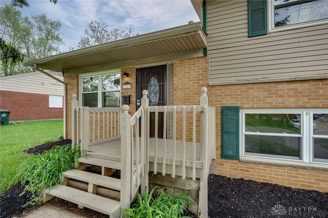 doorway to property with brick siding and a wooden deck