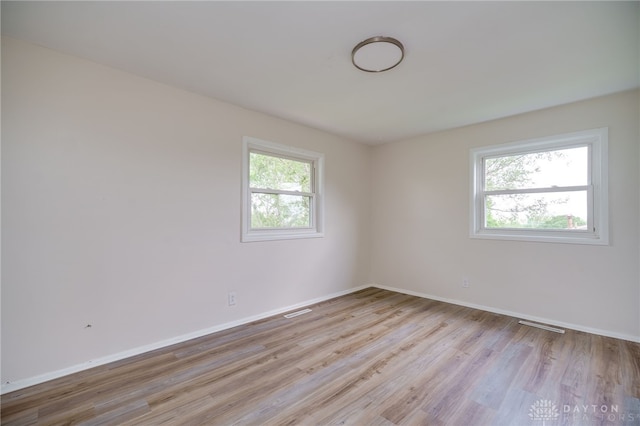 unfurnished room with baseboards, wood finished floors, and visible vents
