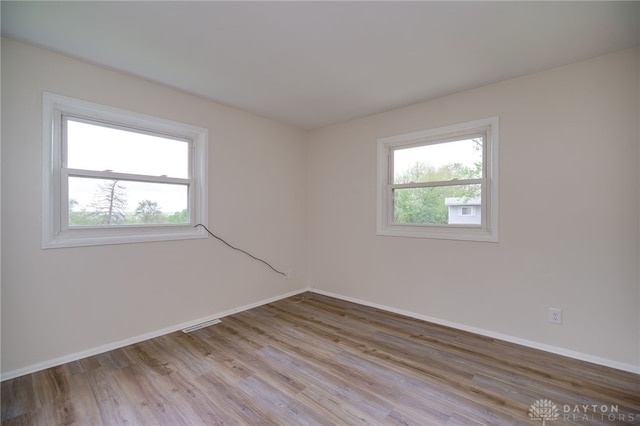spare room with baseboards and wood finished floors
