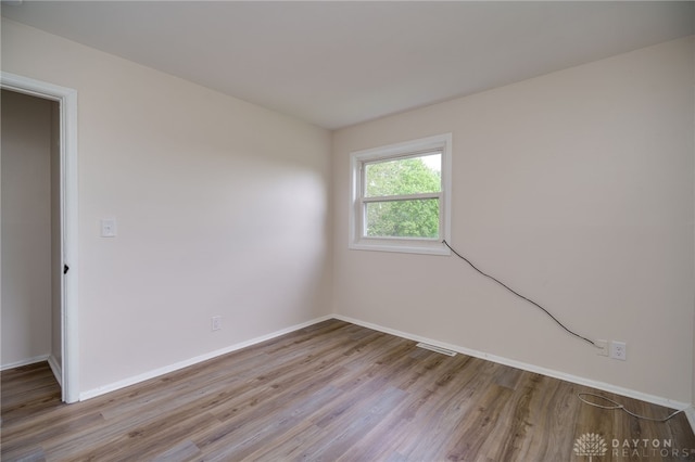 spare room with baseboards, wood finished floors, and visible vents