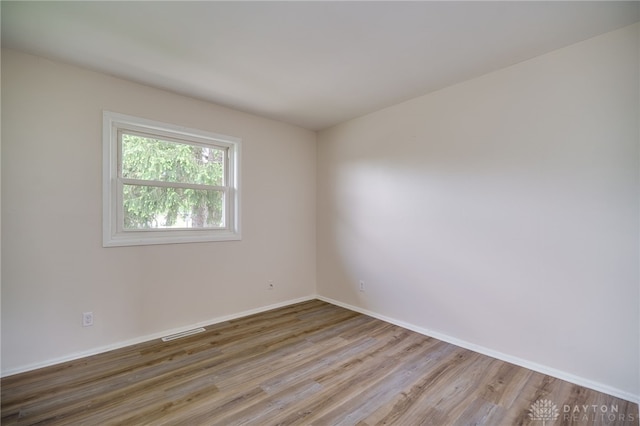 unfurnished room featuring baseboards, visible vents, and wood finished floors