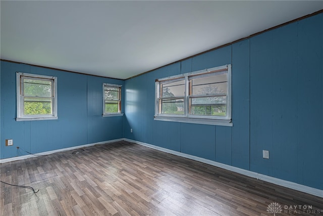 unfurnished room featuring baseboards, a decorative wall, and wood finished floors