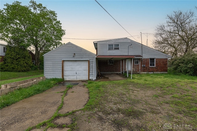 back of house with a lawn, a detached garage, brick siding, and aphalt driveway