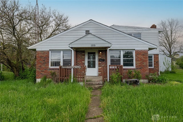 bungalow-style house featuring brick siding and a chimney