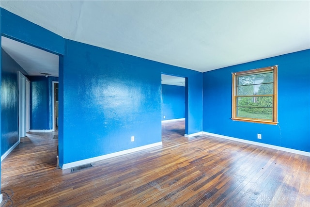 unfurnished room featuring wood-type flooring, baseboards, and visible vents