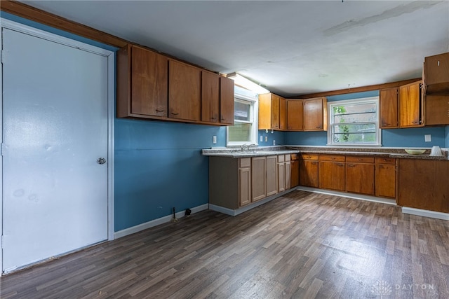 kitchen with brown cabinets, baseboards, dark wood finished floors, and dark countertops