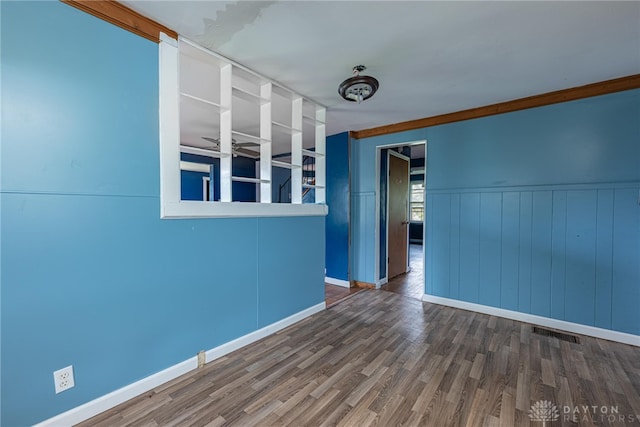 spare room with visible vents, baseboards, wood finished floors, and a wainscoted wall