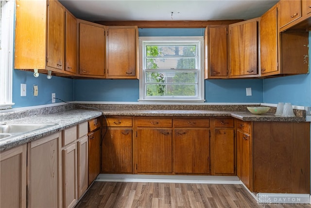kitchen featuring a sink, wood finished floors, and brown cabinets