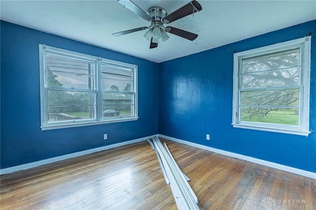 unfurnished room featuring baseboards, a ceiling fan, and hardwood / wood-style flooring