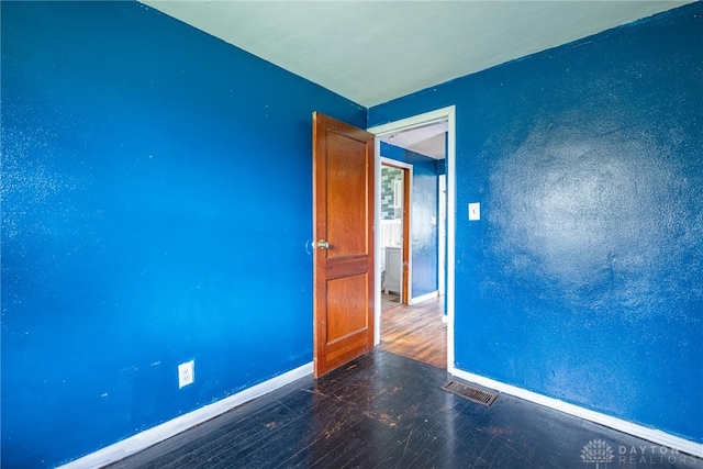 unfurnished room with baseboards, wood finished floors, and visible vents
