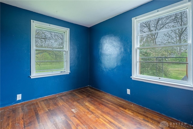 unfurnished room with a healthy amount of sunlight, baseboards, and dark wood-style flooring
